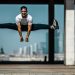 Man performing a split jump on concrete, showcasing fitness and agility.